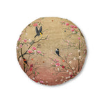Round floor pillow with spring cherry blossom branches and colorful birds on warm gold to rose gradient background