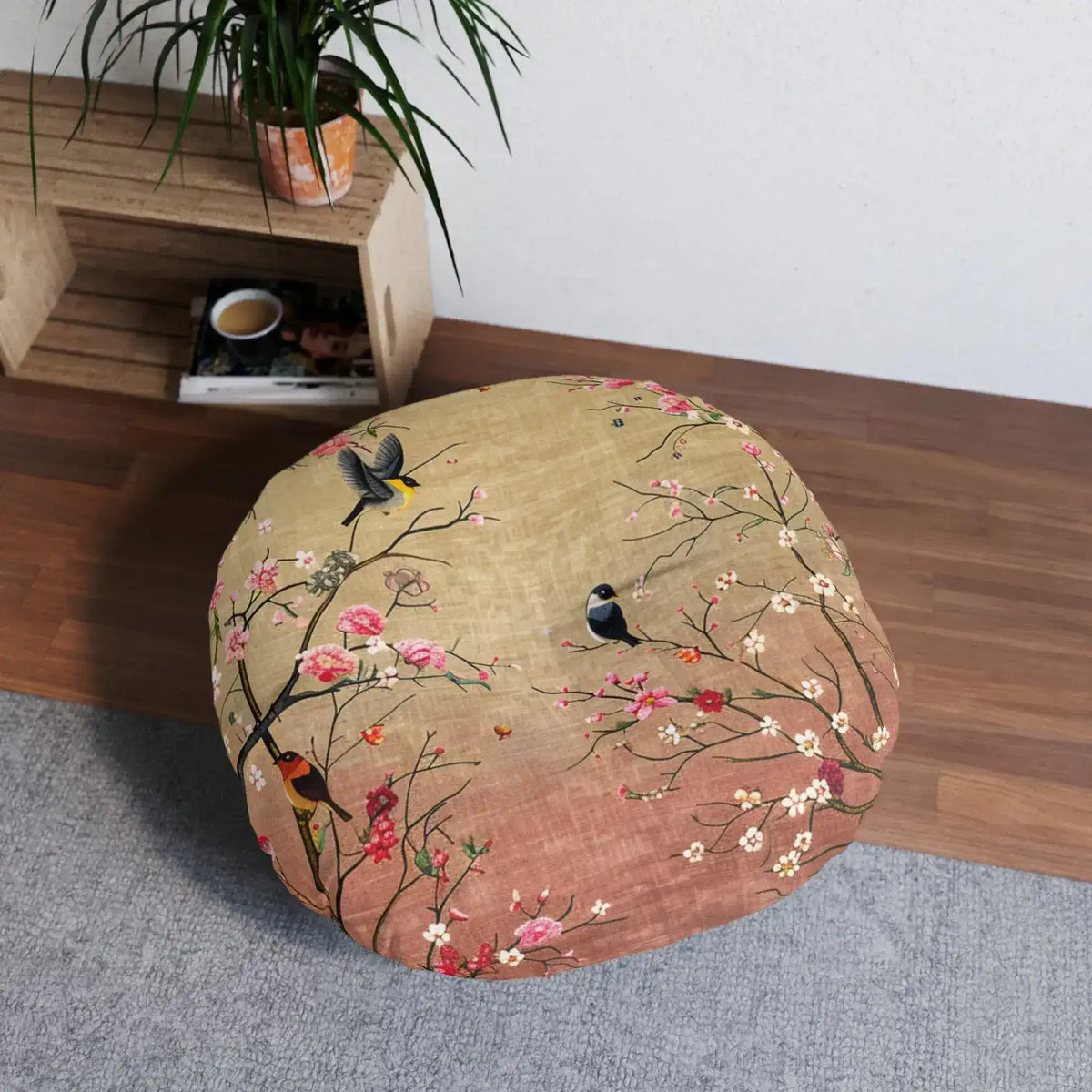 Spring Blossom Birds Floor Pillow in room next to shelf and plant, top-down lifestyle view on gray mat