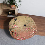 Spring Blossom Birds Floor Pillow in room next to shelf and plant, top-down lifestyle view on gray mat