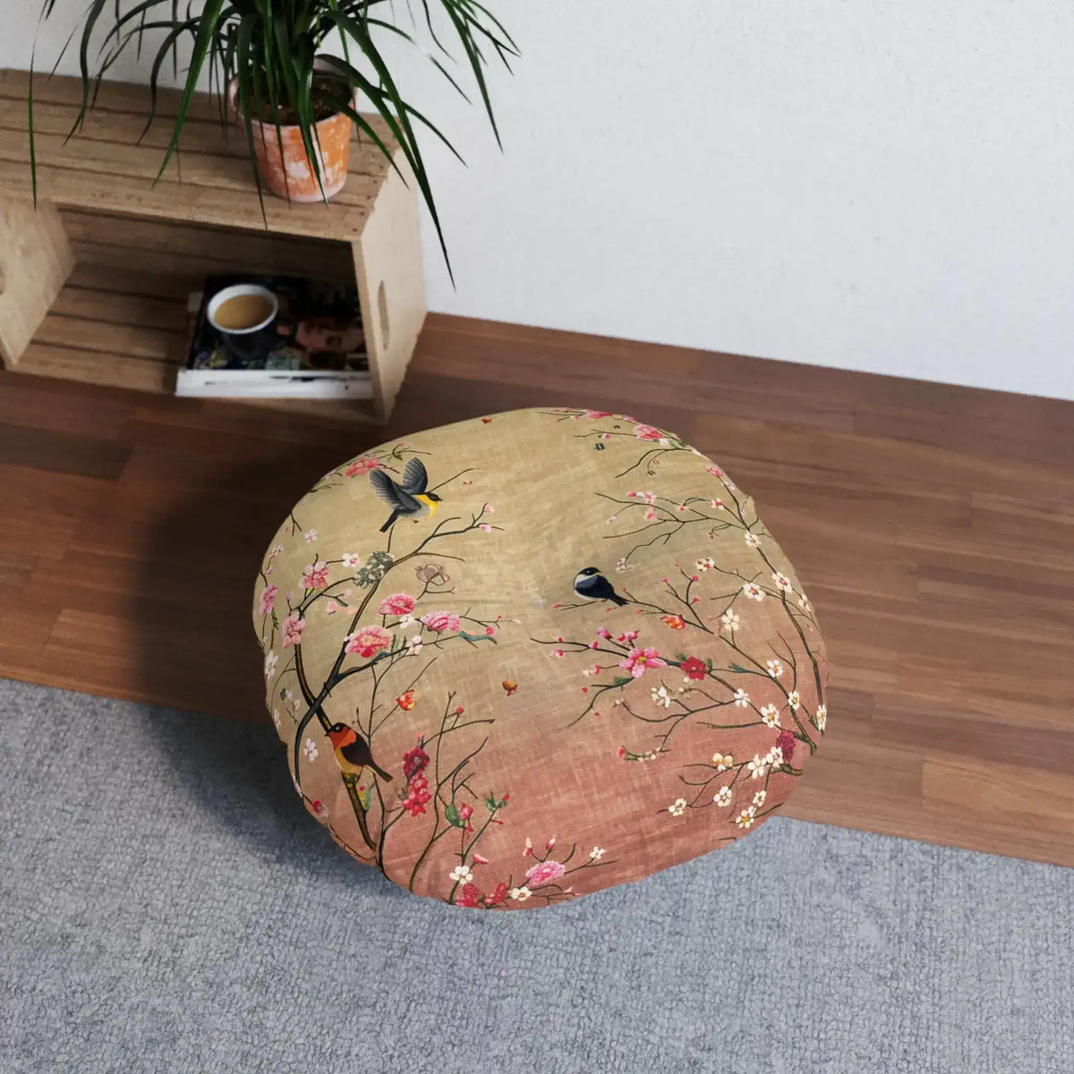 Spring Blossom Birds Floor Pillow on gray rug next to wooden shelving unit with plant, in-room angled lifestyle view