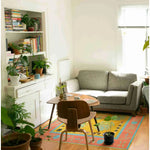 A cozy living room featuring a vibrant Spring Blossom Traditional Hand Tufted Area Rug. The wool rug with boho patterns adds a splash of color against the neutral tones of the sofa and wooden furniture. Perfect for both living room and dining room settings, enhancing the ambiance of a formal dining room.