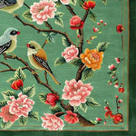 This vibrant square area rug, perfect for a living room, features a hand-tufted wool design with intricate floral and bird motifs. The large area rug showcases detailed pink, red, and yellow flowers, along with perched birds, set against a rich green background. Ideal for adding a touch of nature and elegance to your living space.
