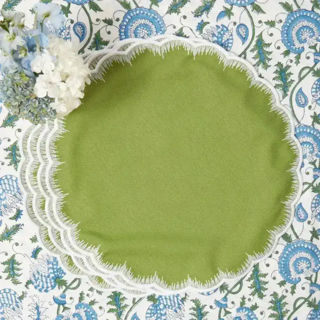 Stack of Lily of the Valley Elegance placemats, sage green round scalloped shape with white fringe border, blue floral cloth