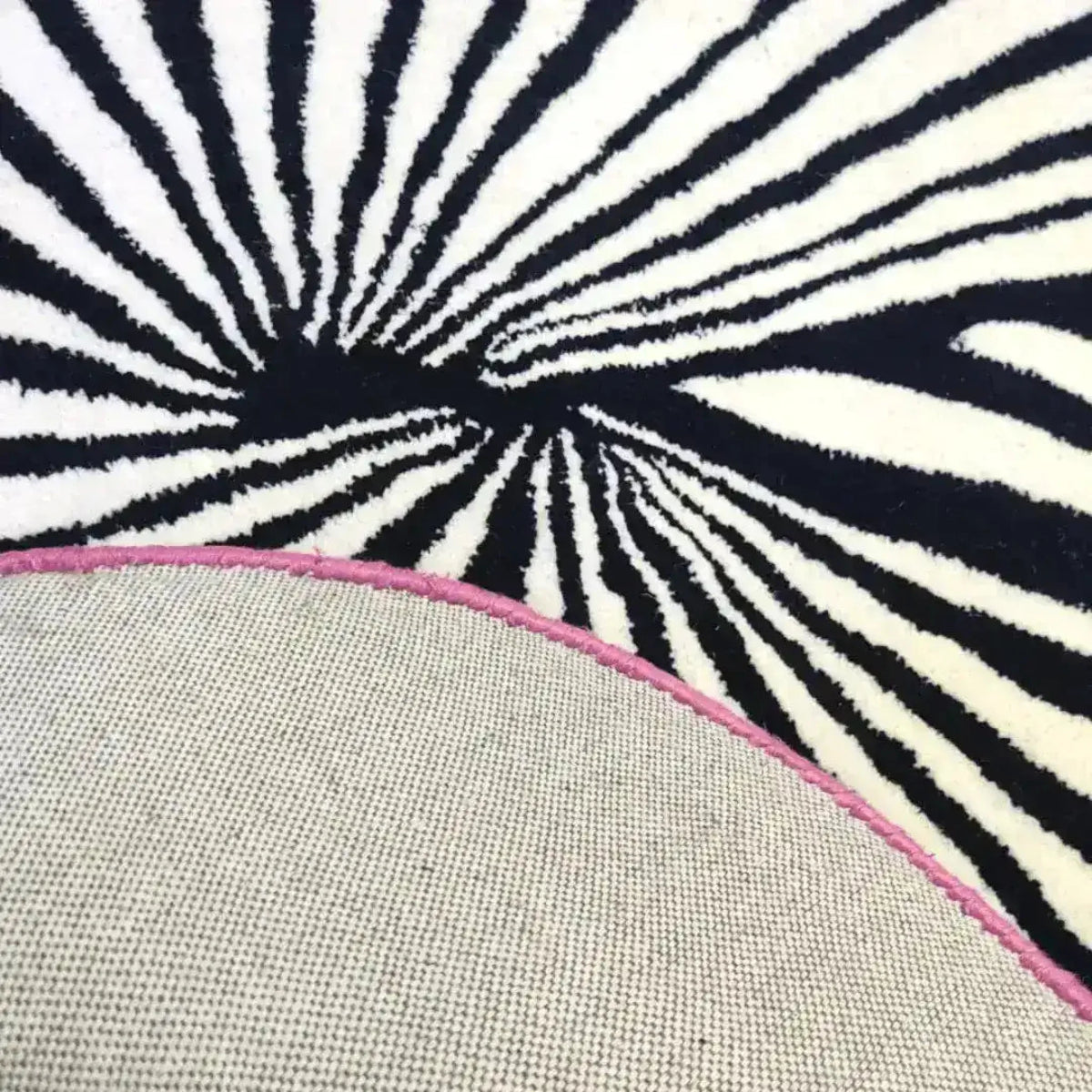 Close-up view of the Step onto the Pink Sun Hand Tufted Wool Rug, showcasing its artistic black and white abstract pattern, perfect for large living room spaces. This vintage rug features a pop of pink along the edge, adding a stylish touch to any area rug setting.