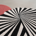 Close-up of a black and white geometric patterned rug with a red circular object partially visible.