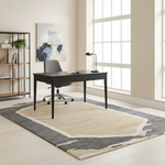 Modern home office with a black desk, chair, and abstract art on a light-colored rug.