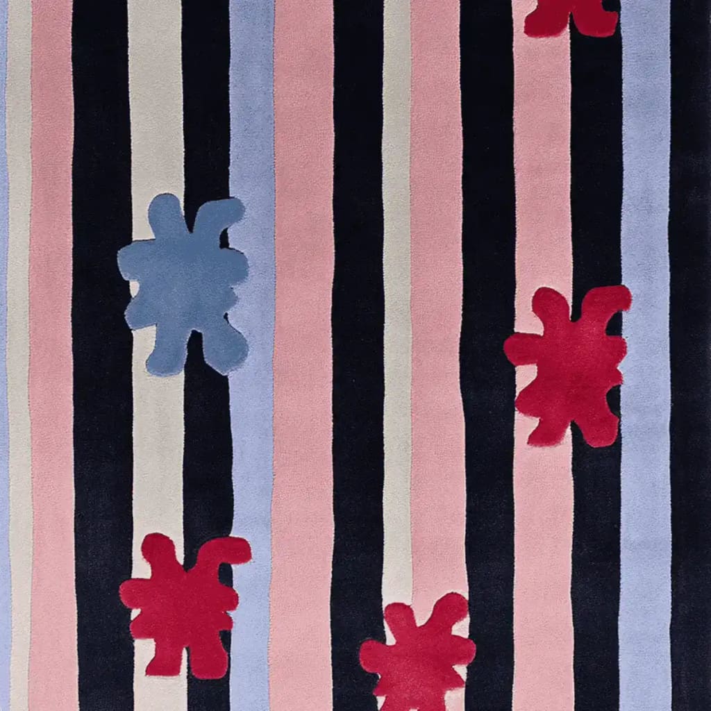 A vibrant area rug featuring bold, vertical stripes in shades of black, pink, and blue, adorned with playful red and blue splat motifs. This contemporary wool rug is perfect for adding a splash of color to living room area rugs and elevating any space with its unique design.