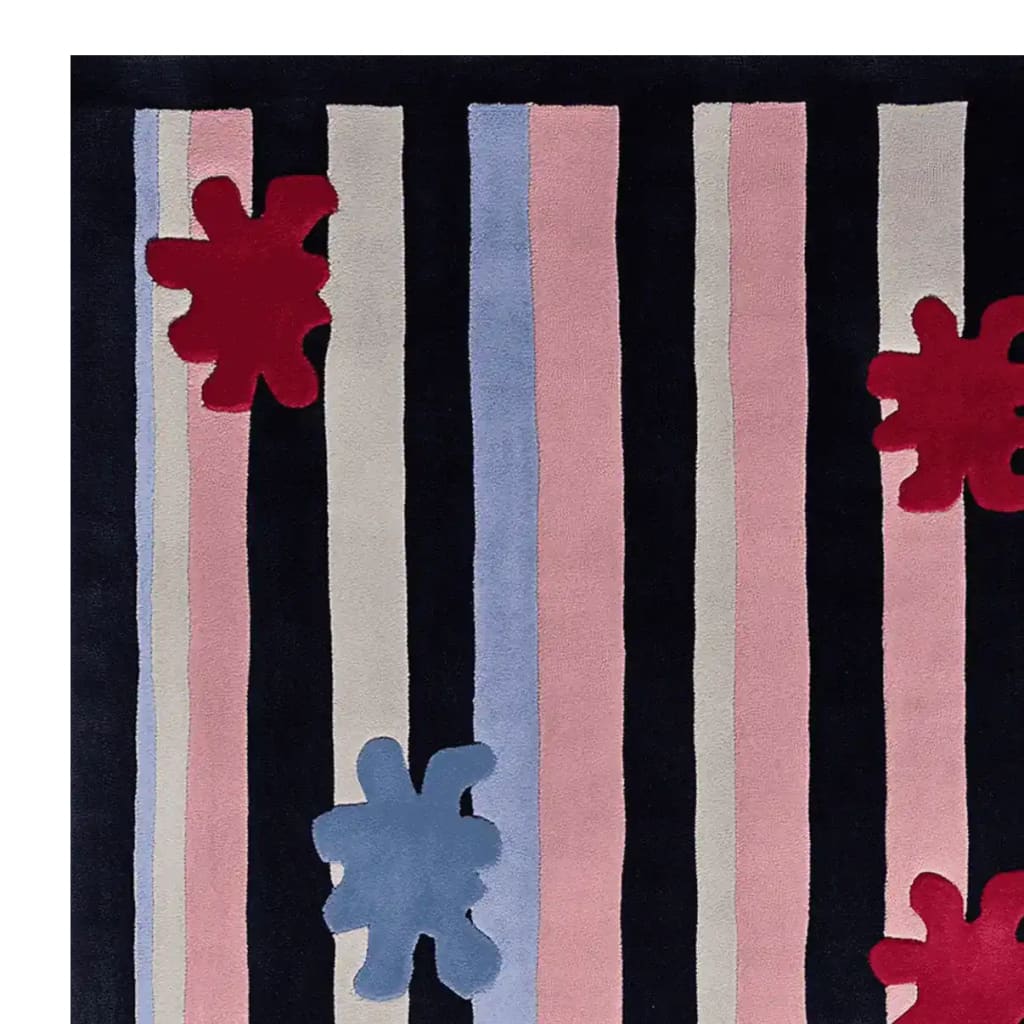 Top view of the Stripe Splat Pop Hand Tufted Rug, a contemporary wool area rug perfect for living rooms. It features bold, vertical stripes in black, pink, and light blue with playful red and blue splat shapes, adding a modern touch to any space.