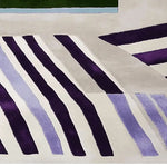 This contemporary area rug features a striking collision of stripes in bold purple and soft lavender, ideal for large living rooms. The wool rug showcases a modern design with a blend of geometric patterns, enhancing any space's aesthetic appeal.