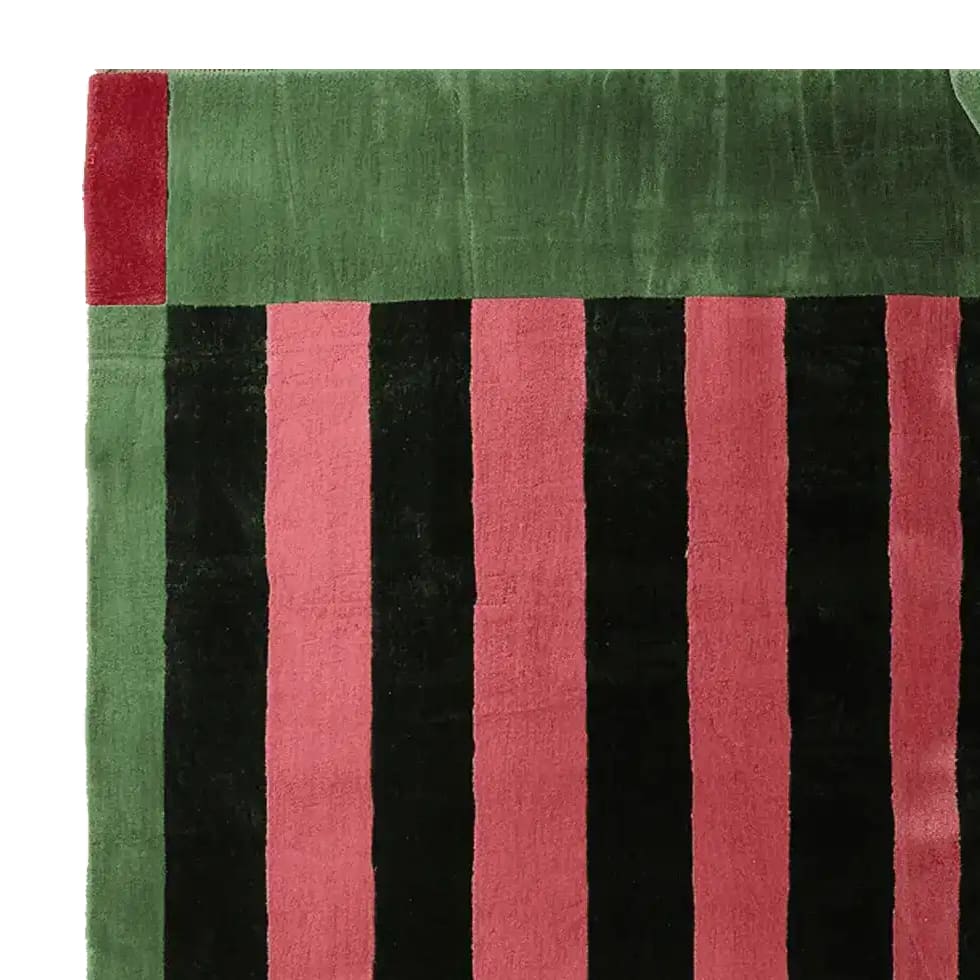 Close-up view of the Structured Red Rhythm Hand Tufted Rug showcasing its bold black and red stripes with green accents. Perfect as an area rug, this contemporary wool rug adds a vibrant touch to any living room.