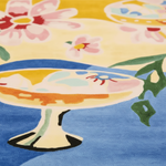 Decorative rug with floral design and cake illustration on a yellow and blue background