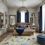 Luxurious bedroom with a large bed, floral rug, and decorative mirrors.