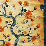 Close-up view of the Sunlit Sakura Hand Tufted Rug, an exquisite area rug perfect for living room and dining room spaces. This floral wool rug features vibrant orange blossoms on a soft, warm background, bringing elegance and style to any dining room or under a dining table.