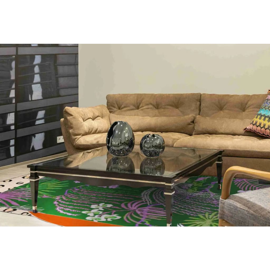 Stylish living room featuring a Sunset in the Jungle hand tufted wool area rug. The vibrant pattern adds a pop of color beneath a sleek glass coffee table, surrounded by a comfortable beige sofa, perfect for enhancing dining rooms or bedrooms.