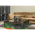 Stylish living room featuring a Sunset in the Jungle hand tufted wool area rug. The vibrant pattern adds a pop of color beneath a sleek glass coffee table, surrounded by a comfortable beige sofa, perfect for enhancing dining rooms or bedrooms.