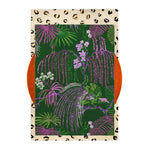 Vibrant hand-tufted wool rug featuring a lush jungle design with purple and green foliage on a deep green background, ideal for adding an exotic touch to a dining room or bedroom. The area rug is framed by a bold border with leopard print accents, perfect for formal dining room aesthetics.