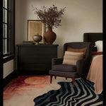 A stylish living room featuring a contemporary hand tufted area rug with a sunset waves design, perfect for adding warmth. The 8x10 wool rug complements the modern decor, featuring a cozy armchair and elegant vases.