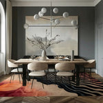 A contemporary living room featuring the Sunset Waves Hand Tufted Viscose Rug, an area rug with abstract patterns resembling waves in shades of red, orange, and black. The rug is placed under a stylish dining table set, complementing the modern decor with its artistic design. Perfect for adding a touch of elegance to living room spaces, especially in 8x10 dimensions, this wool rug enhances the room's cozy ambiance.