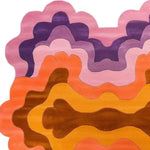 A vibrant, hand-tufted wool rug showcasing swirling colors in shades of pink, purple, orange, and brown. This contemporary area rug, perfect for a living room, features an abstract, wavy pattern, ideal for adding a splash of color to any space. It is a standout piece among 8x10 living room rugs, offering a blend of modern design and cozy wool texture.
