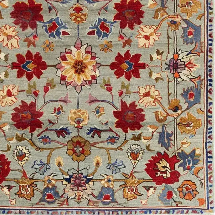 This is a detailed view of a Symmetrical Hand Tufted Rug, showcasing a vibrant floral pattern with red, yellow, and blue motifs against a soft background. Perfect for adding a vintage touch to your living room, this wool rug is an ideal area rug for large spaces, combining elegance and style.