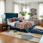 Modern bedroom with teal upholstered bed, geometric rug, and colorful decor