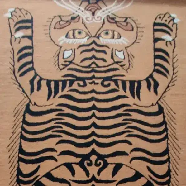 A close-up view of the Tanned Jungle Cat Hand Tufted Wool Rug, showcasing a striking abstract tiger design. This area rug, perfect for living rooms or as an 8x10 piece for bedrooms, features bold black stripes on a tan background, highlighting its luxurious wool texture.