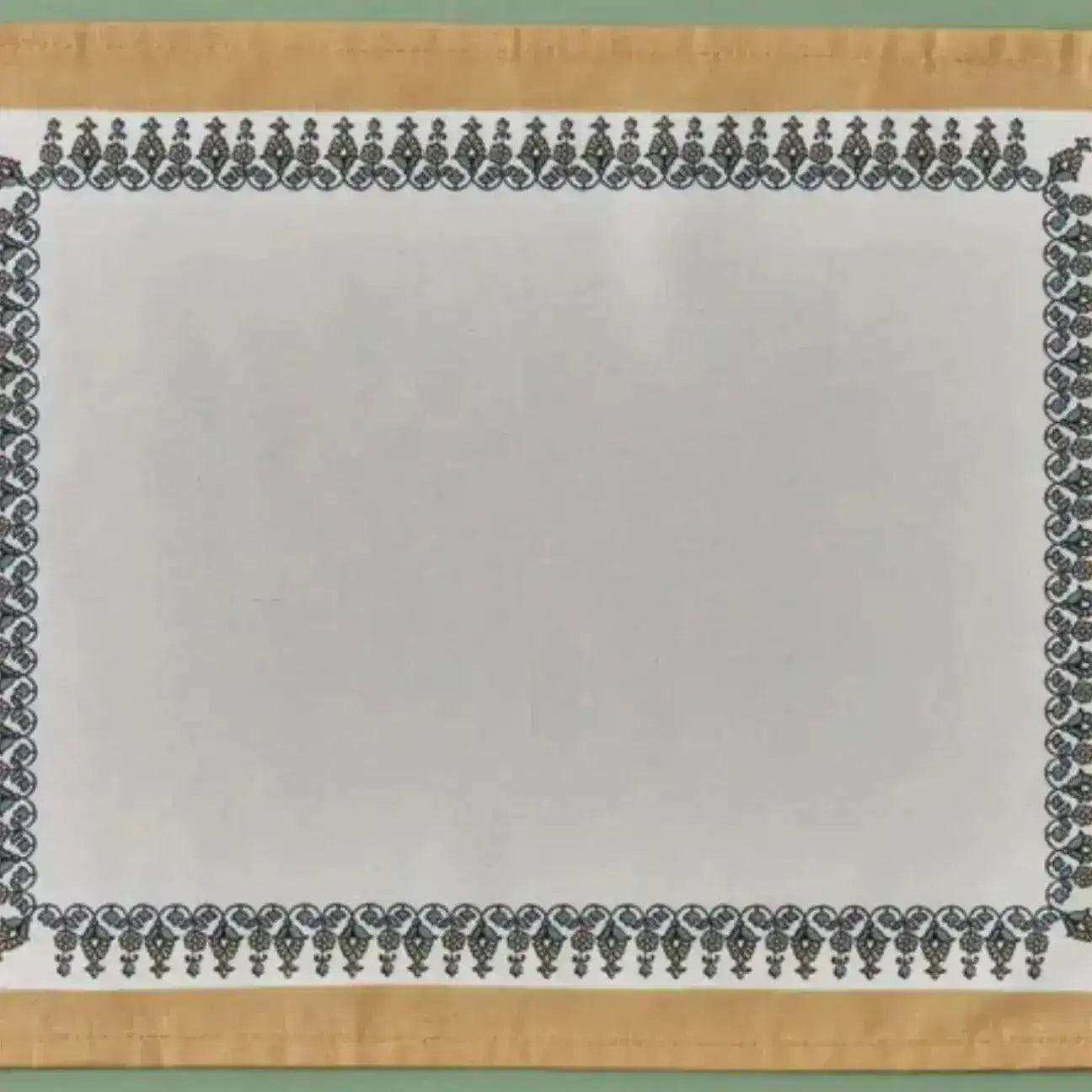Tassel Trimmed placemat detail showing white linen center with black ornate border and gold fabric edge