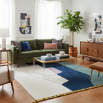 Modern living room with a green sofa, colorful rug, and decorative items.