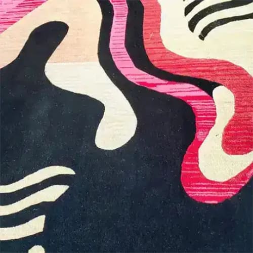 Close-up view of the Terracotta Twist Hand Tufted Rug, showcasing its abstract design with bold, wavy patterns in red, pink, and cream hues against a dark backdrop. This contemporary wool rug is perfect for large living rooms or dining room areas, offering a stylish and modern touch to any space.