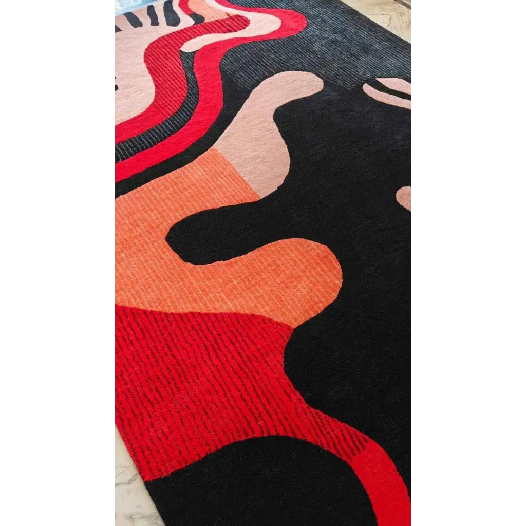 Colorful abstract patterned rug with red, black, and orange colors on a wooden floor.