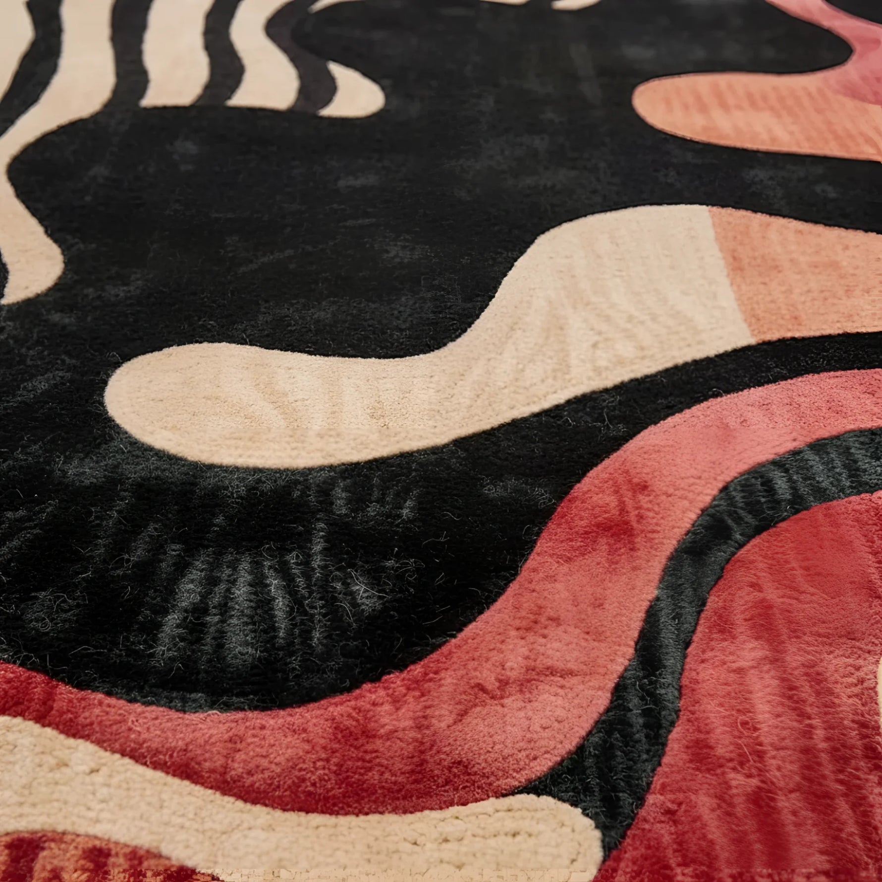 Close-up of a textured rug with wavy patterns in black, beige, and red.