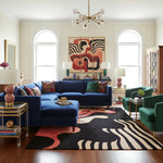 Living room with a blue sofa, colorful rug, and abstract art on the wall.