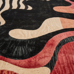 Close-up of a textured rug with wavy patterns in black, beige, and red.