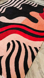 Colorful abstract patterned rug with black, red, and pink colors on a neutral background.