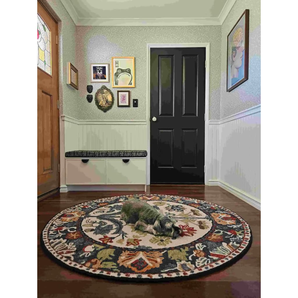 A beautifully designed Blossom Grace Hand Tufted Round Rug adds elegance to a cozy entryway. This floral area rug, perfect for both dining room area rugs and living room settings, features intricate patterns in vibrant colors, creating a warm and inviting atmosphere. A small dog rests comfortably on this wool rug, showcasing its plush texture and comfort.