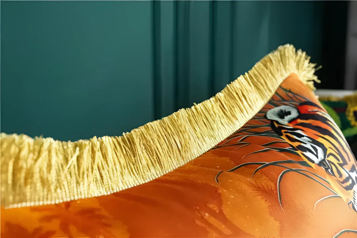 Close-up view of a decorative throw pillow featuring golden fringe and a vibrant animal print design, perfect for adding a touch of elegance to any space.