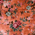 The Secret Garden Hand Knotted Rug features a vibrant floral design on a warm, orange background. This wool area rug, perfect for living room and dining room settings, adds a touch of elegance to formal dining spaces with its intricate floral patterns.