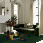 Elegant living room featuring the Three Evil Eyes Green Hand Tufted Wool Area Rug. This vintage rug with an abstract design adds a sophisticated touch, perfect as a dining table rug or in any bedroom, dining room, or as a kitchen runner rug. Its rich green hues complement the plush green sofa and modern decor.
