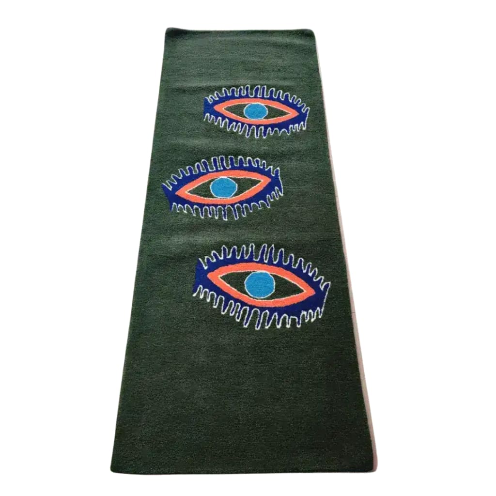 The Three Evil Eyes Green Hand Tufted Wool Rug features a striking design with three large, abstract eye motifs set against a rich green background. This area rug is perfect for adding a bold statement to your dining room, kitchen, or bedroom. Its vibrant colors and unique pattern make it a versatile choice for use as a dining table rug, kitchen rug, bathroom runner rug, hallway runner rug, or vintage-inspired decor.