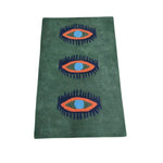 A vibrant green hand-tufted wool area rug featuring a unique design of three stylized, abstract eyes in bold colors. Perfect as a vintage rug for bedroom decor or as a standout piece in kitchens and hallways. This wool rug's distinctive pattern adds a touch of personality to any room, whether used as a bathroom runner or a hallway runner rug.