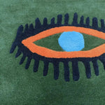 A vibrant hand-tufted wool area rug featuring a bold abstract eye design with striking orange and blue colors against a rich green background. Perfect for adding a touch of artistic flair to your kitchen, hallway, or bedroom. This vintage-inspired rug functions beautifully as a bathroom runner rug or a stylish rug for the bedroom, enhancing any space with its unique pattern.