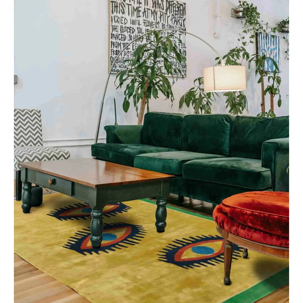 A vibrant area rug in a living room setting, showcasing its unique 'Three Evil Eyes' design. The wool rug features a bold pattern that adds a vintage touch to the space, complementing the green velvet sofa and wooden coffee table. Ideal for both dining room and formal living room settings.
