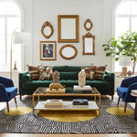 Modern living room with a green sofa, blue chairs, and decorative mirrors on the wall.