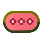 Top view of a unique oval area rug featuring three red flowers on a pink background, bordered by shades of green. This hand-tufted wool rug adds a vibrant touch to any living room, perfect for enhancing your home decor with stylish living room area rugs.