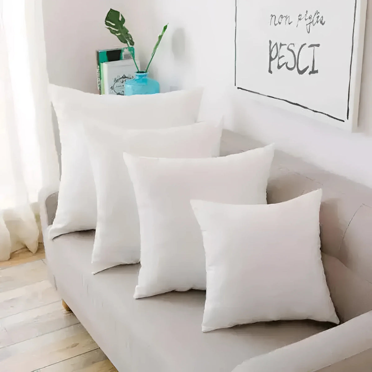 Collection of white throw pillows arranged on a couch, showcasing various sizes for decorative purposes.