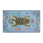 Tibetan tiger tea towel horizontal flat-lay, yellow-black striped tiger on light blue cotton with multicolor Tibetan border