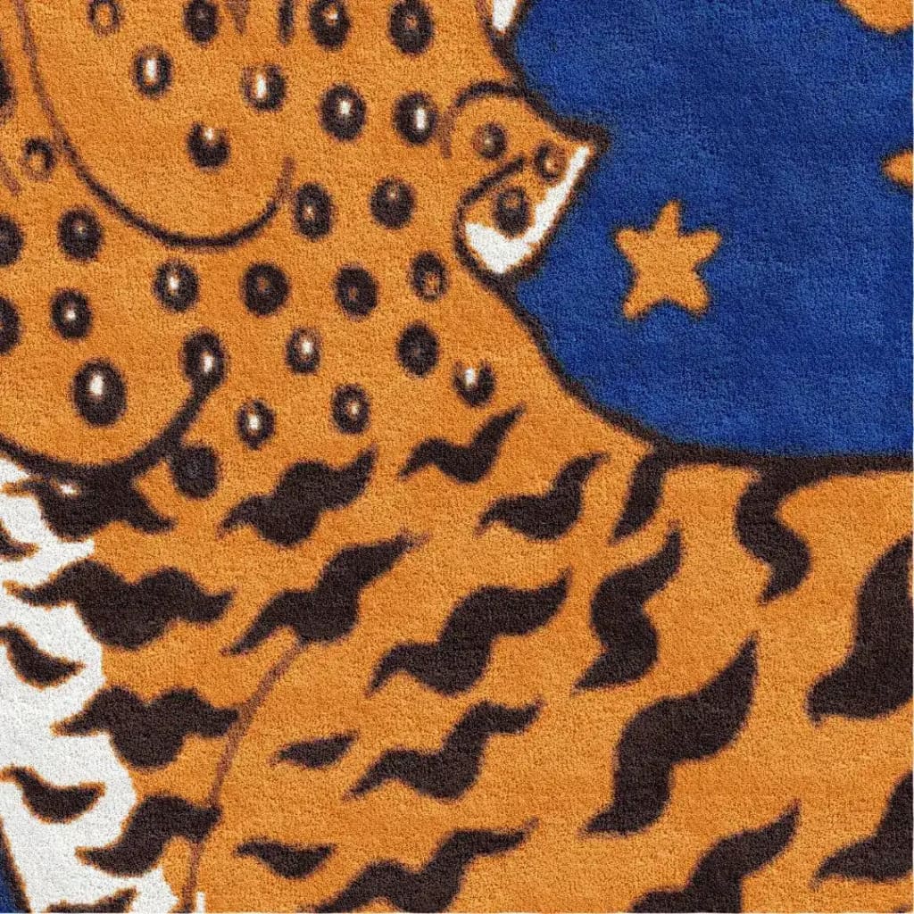 Close-up view of a Tibetan Tiger Starry Night Scallop Hand Tufted Wool Rug featuring bold orange and black tiger patterns with a rich blue starry backdrop. This vibrant wool rug is perfect for adding a touch of vintage charm to large living rooms, or as a statement piece in kitchens and hallways.