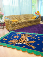A vibrant Tibetan Tiger Starry Night Scallop Hand Tufted Wool Rug placed in a cozy living room. The area rug features a striking tiger design in rich colors, perfect for large living room rugs or as a vintage rug accent. The plush wool rug complements the eclectic decor, adding warmth and texture to the space. Ideal for use as kitchen rugs, bathroom runner rugs, or hallway runner rugs, this versatile piece fits perfectly in living room rugs 8x10 settings.