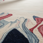 Close-up of a textured rug with floral patterns in red, blue, and beige.
