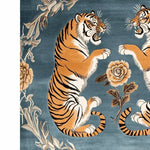 A striking hand-tufted wool rug featuring two majestic tigers facing each other on a rich blue background, surrounded by elegant floral designs. This vintage-style area rug adds a bold yet sophisticated touch to large living rooms, blending nature-inspired elements with a classic aesthetic.